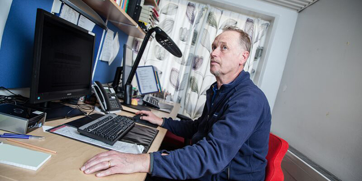 Michael Lindroths vid sitt skrivbord framför datorn